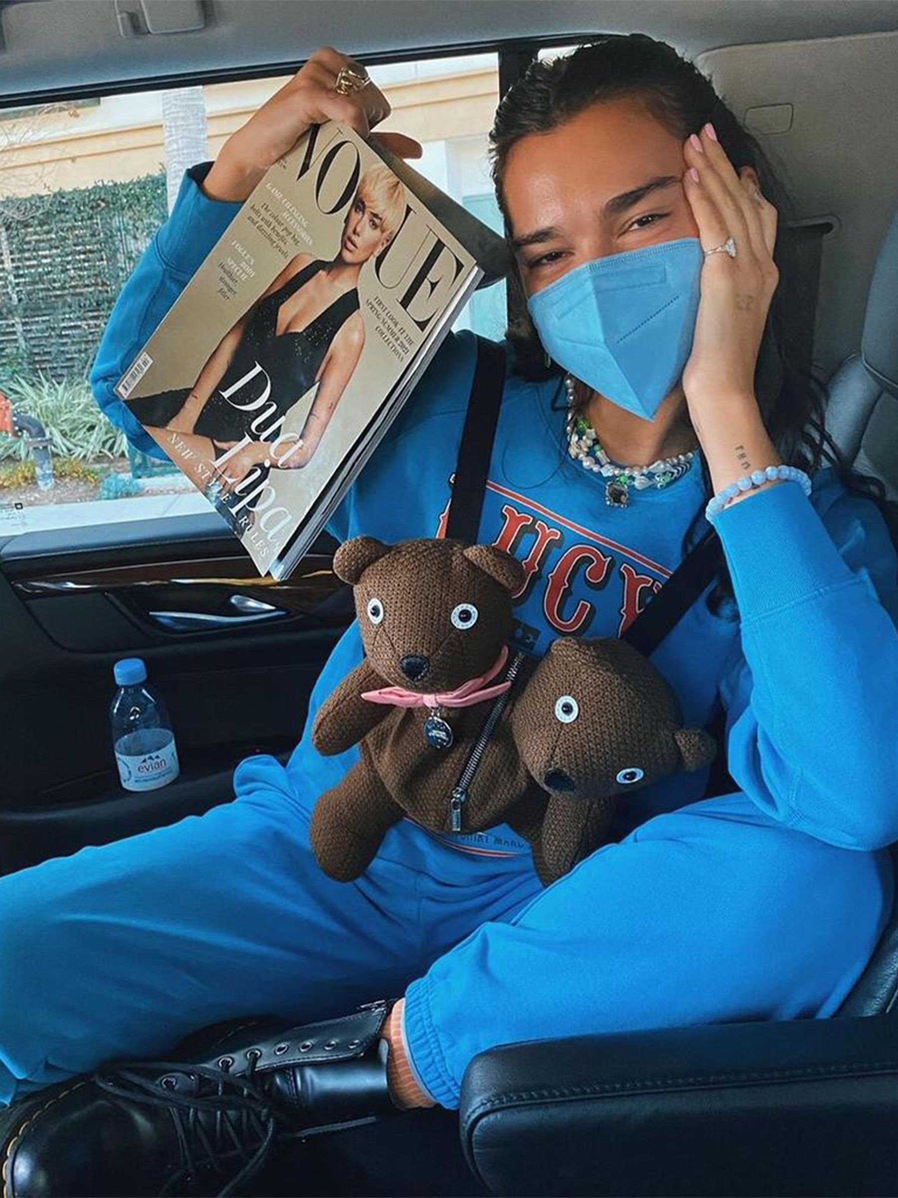 Dua Lipa poses in a car with a Vogue magazine and a double-headed Teddy Bear bag from Heaven by Marc Jacobs