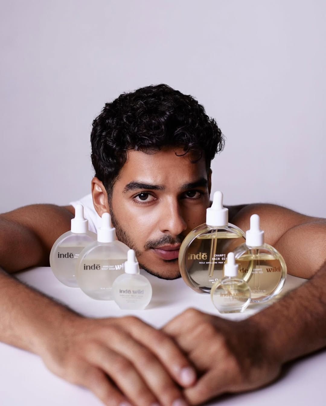 Ishaan Khatter posing with Inde Wild's haircare range (a scalp serum and champi oil)