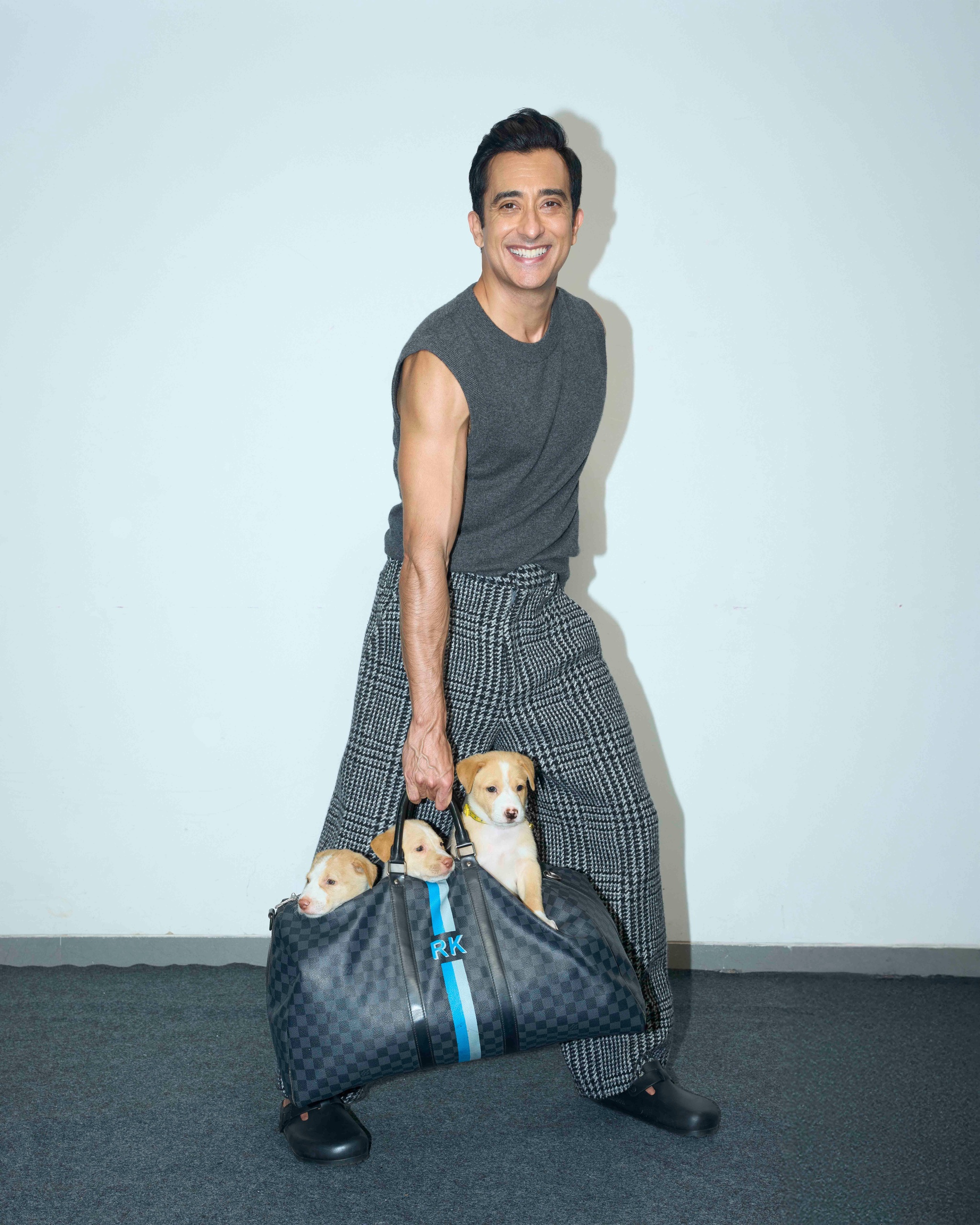 Rahul Khanna posing with puppies in a muscle tee