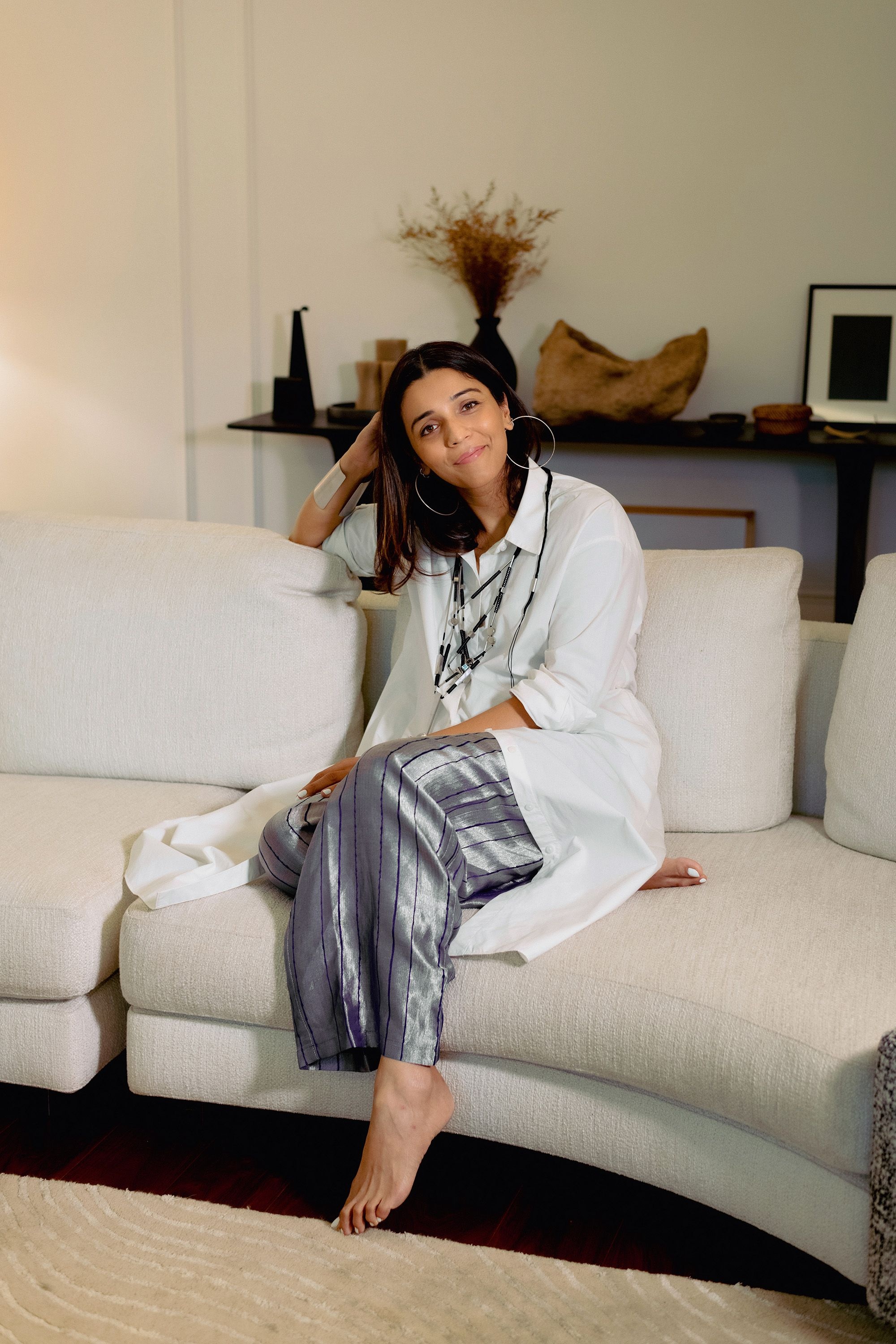Designer and founder of 431-88 Shweta Kapur sitting on her rounded couch in her New Delhi home