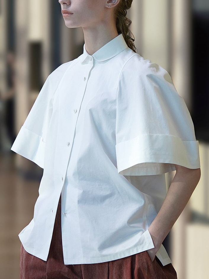 A model wearing a white shirt from Japanese clothing brand Support Surface