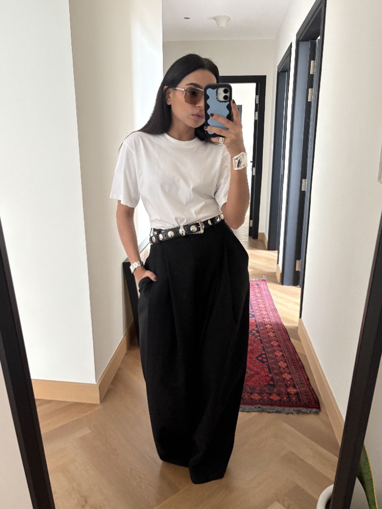 Personal stylist Amrita Singh in a white T-shirt and black trousers, accessorised with a belt, sunglasses and silver cuff