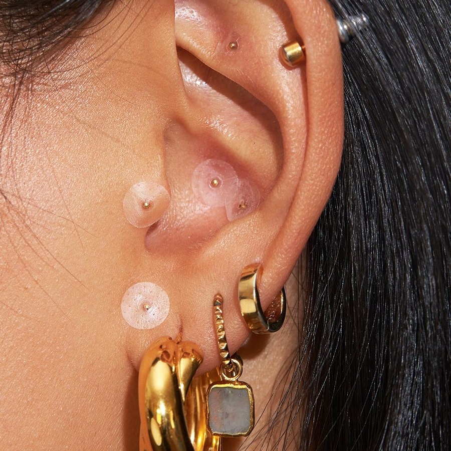 Ear seeding swaps needles for gold or crystal beads, merging tradition with a new kind of wearable therapy