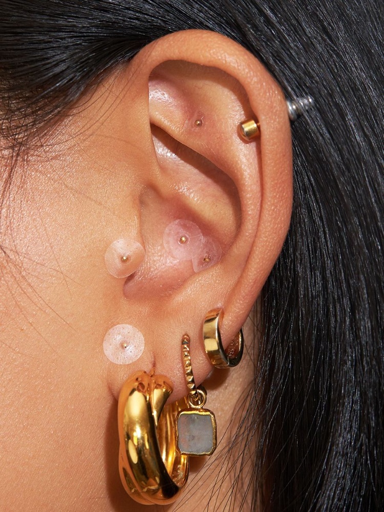 Ear seeding swaps needles for gold or crystal beads, merging tradition with a new kind of wearable therapy