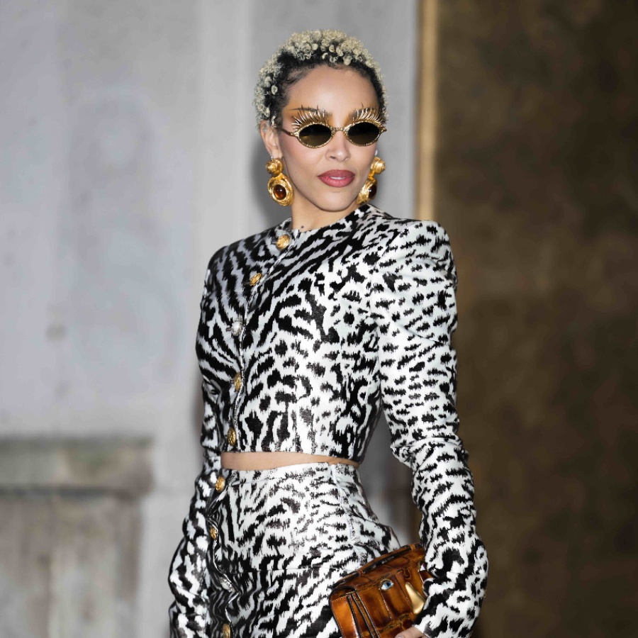 Doja Cat at Paris Fashion Week wearing bejwelled sunglasses and a trompe l'oeil hand hold ring