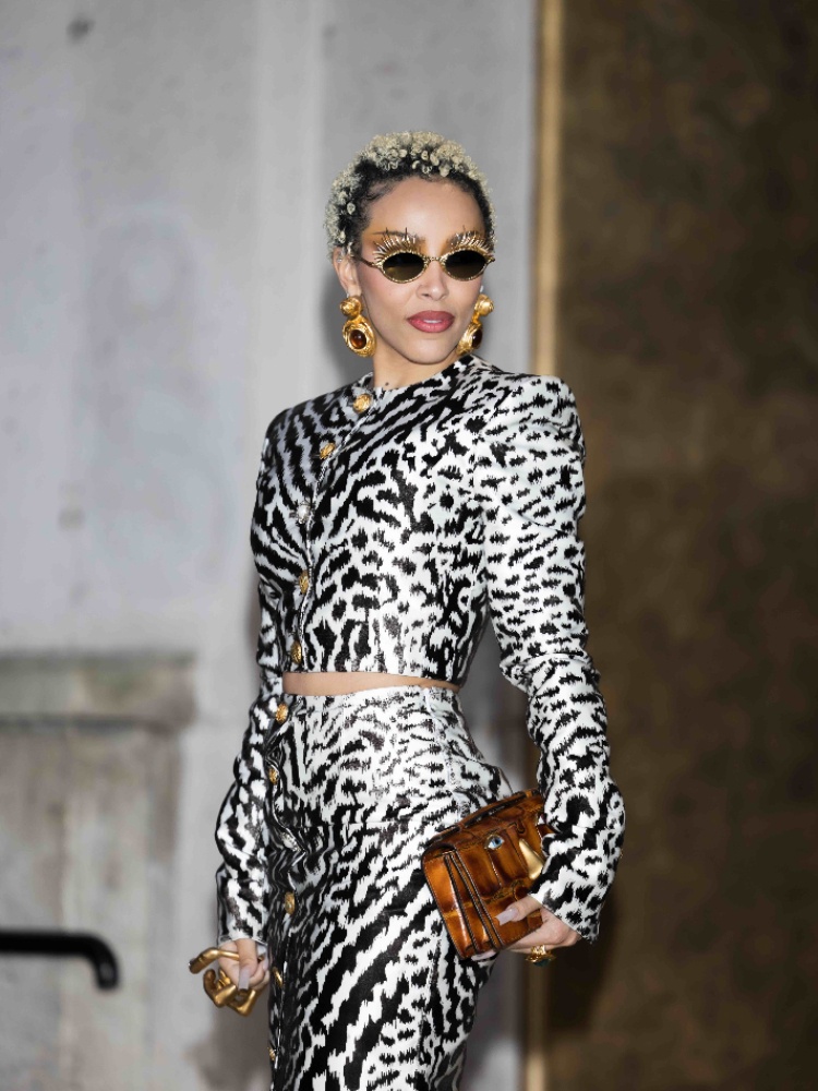 Doja Cat at Paris Fashion Week wearing bejwelled sunglasses and a trompe l'oeil hand hold ring