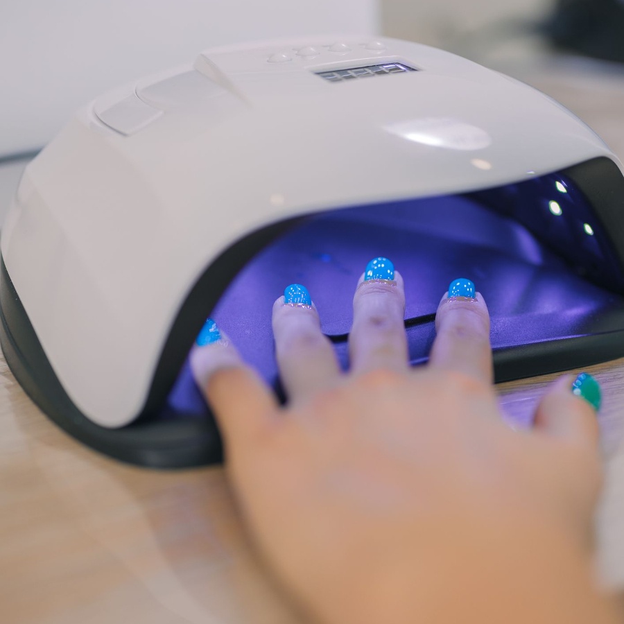 Gel nail polish being cured under a UV light at a nail salon