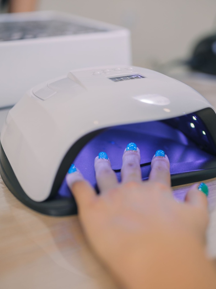 Gel nail polish being cured under a UV light at a nail salon