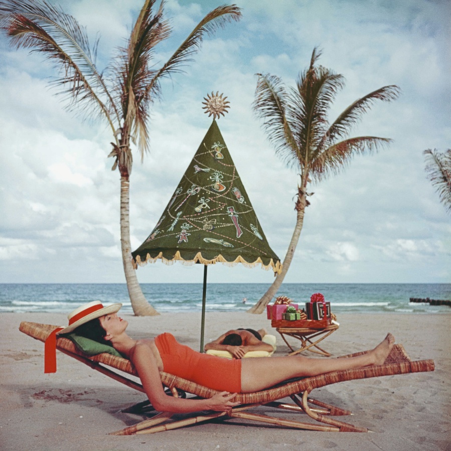 A woman lying on a beach iin a one-piece swimsuit