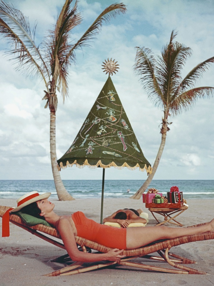 A woman lying on a beach iin a one-piece swimsuit
