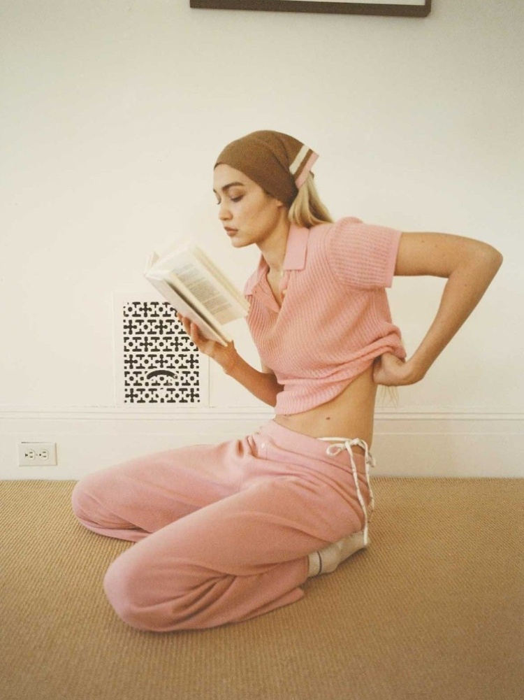 Model Gigi Hadid in a pink pyjama set reading a book
