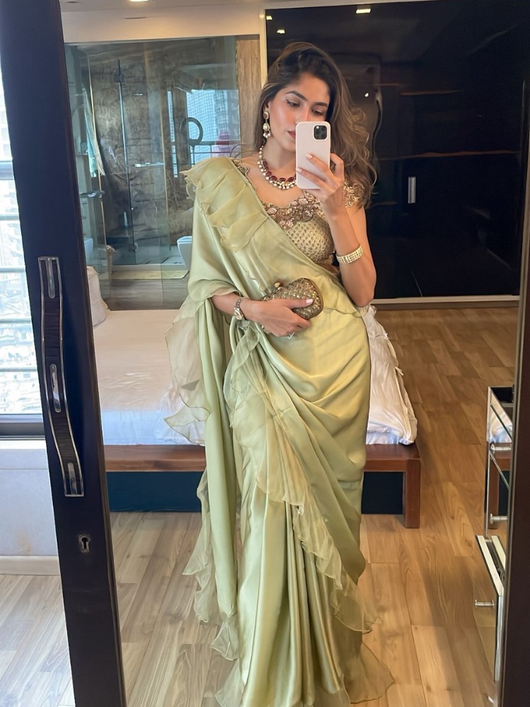 Content creator Isha Sutaria in a sage green floral blouse and ruffled sari