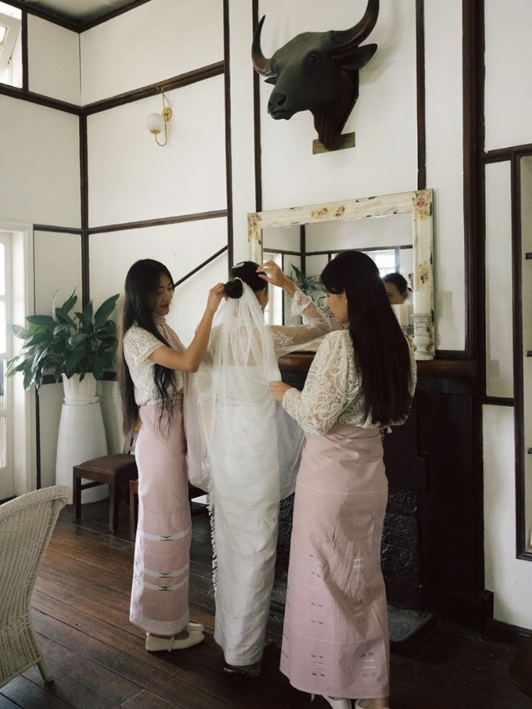 A Kintem bride with her bridesmaids, all wearing contemporary white and pink mekhelas