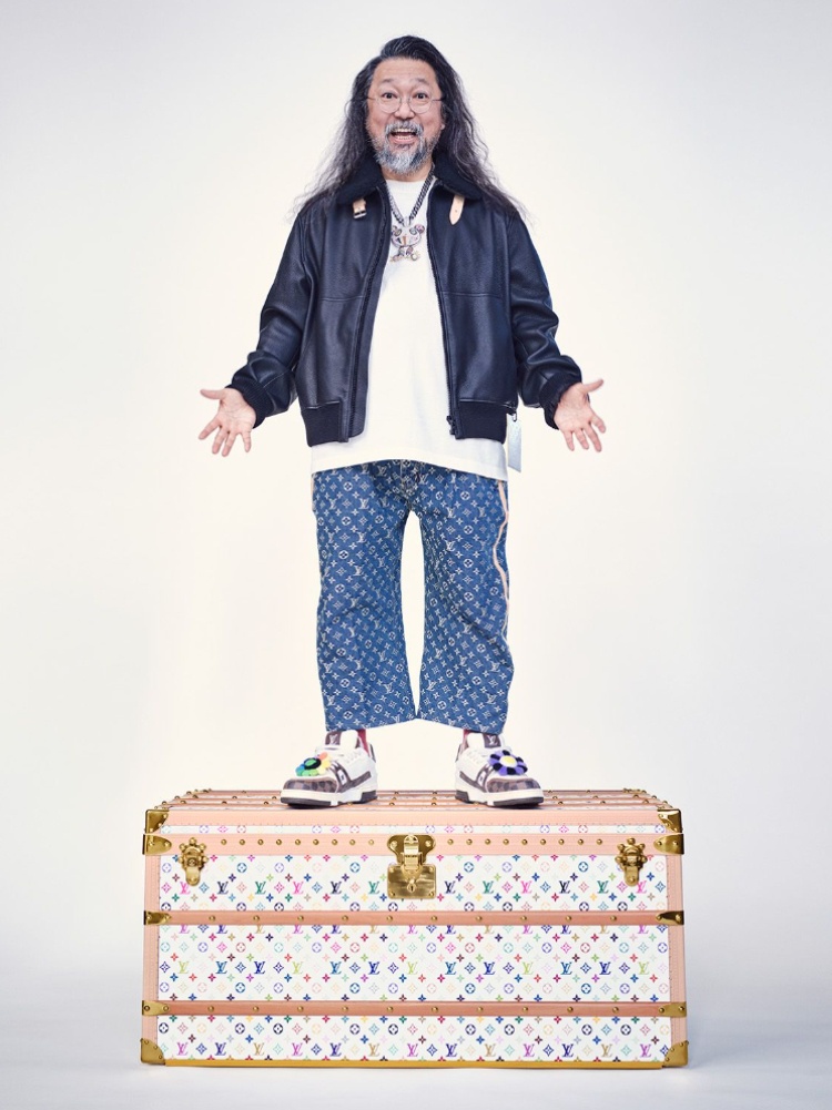 Japanese artist Takashi Murakami standing on a Louis Vuitton trunk with the multicolour monogram motif