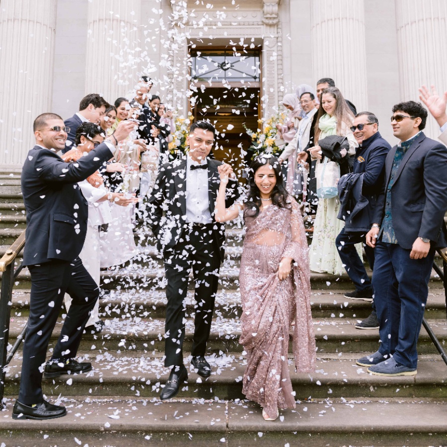 Meera and Ash on the steps of Old Marylebone Town Hall in London on their wedding day