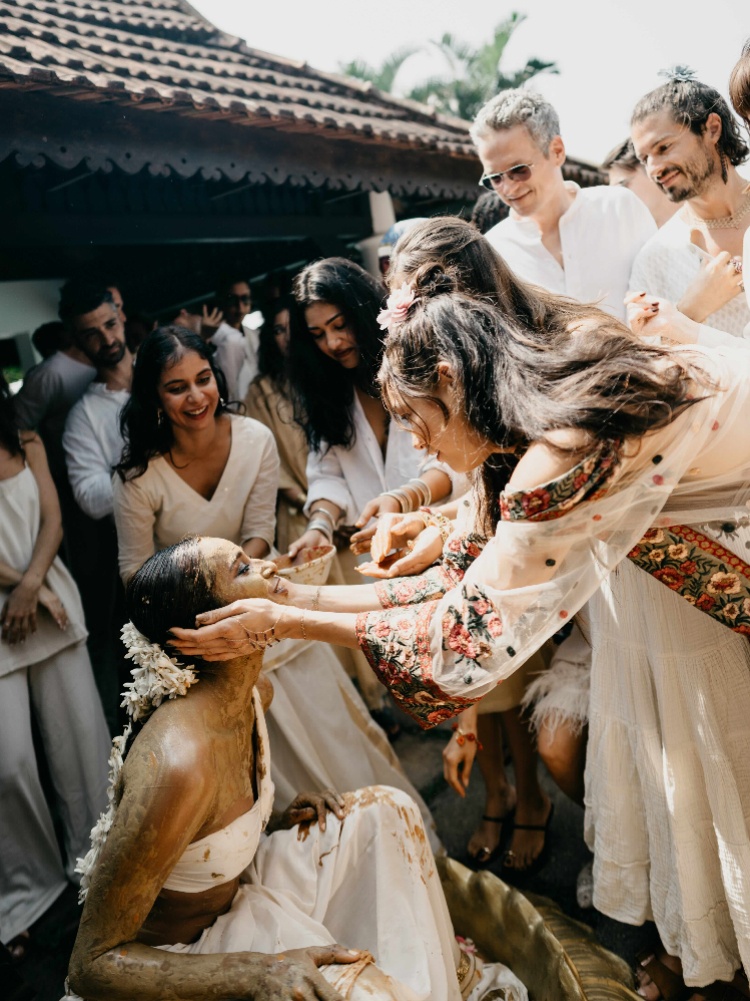 Nidhi Sunil seated in an urli, surrounded by friends at her haldi ceremony