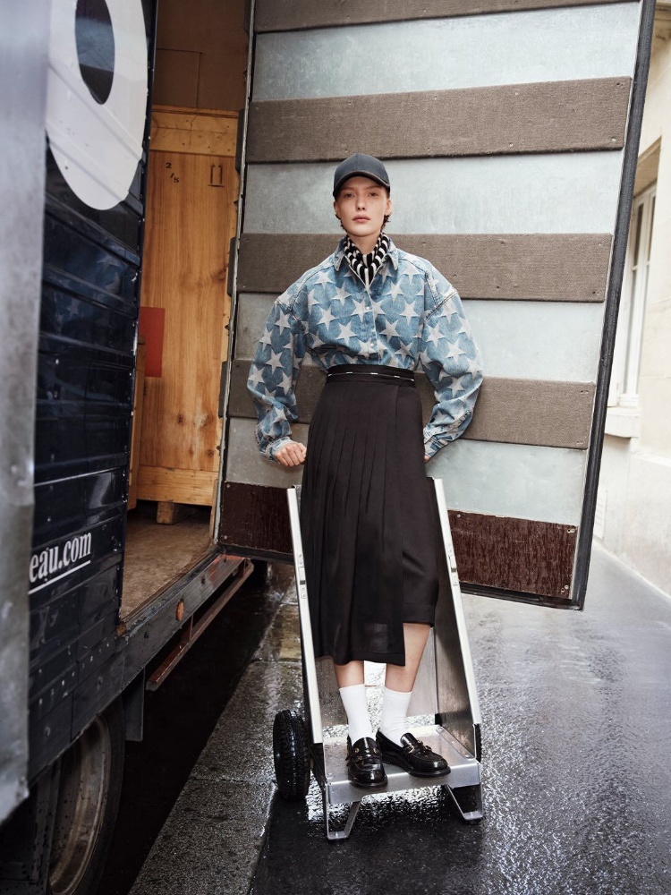 A Sandro model wearing a starry denim overshirt with an asymmetrical pleated skirt