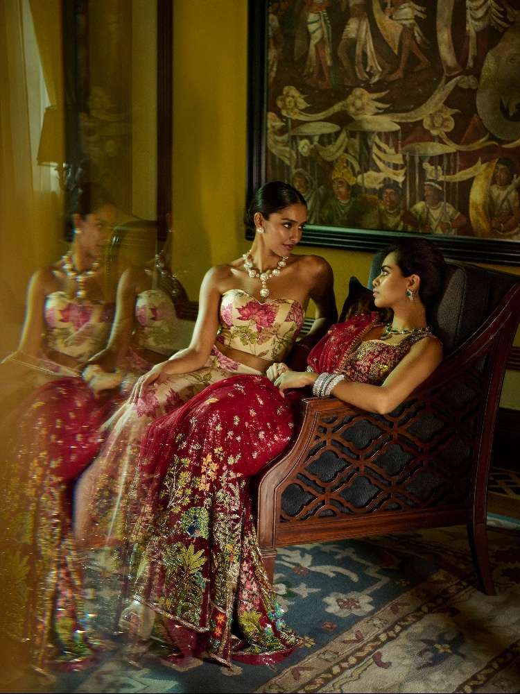 A model in a Gopi Vaid corset and lehenga sitting next to a model in a Rahul Mishra sari