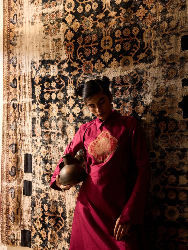 18th-century Khotan carpet from East Turkestan featuring pomegranate motifs, symbols of fertility. On Anika: Payal Khandwala kurta; Pepper Coin jewellery